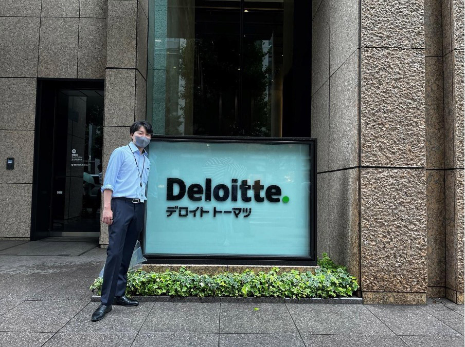 入社したデロイトトーマツ本社の前に立つ秋山さん=2022年8月、本人提供